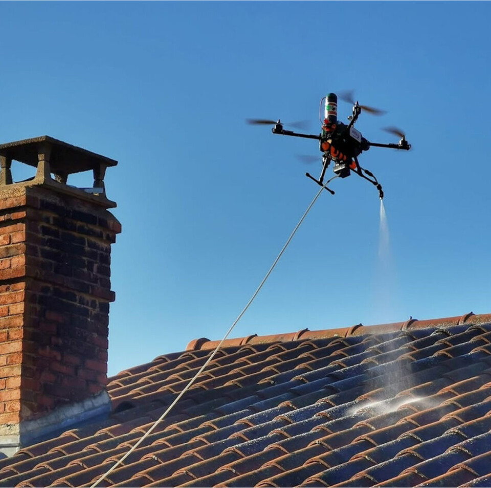 Drone with high-pressure spray cleaning a rooftop